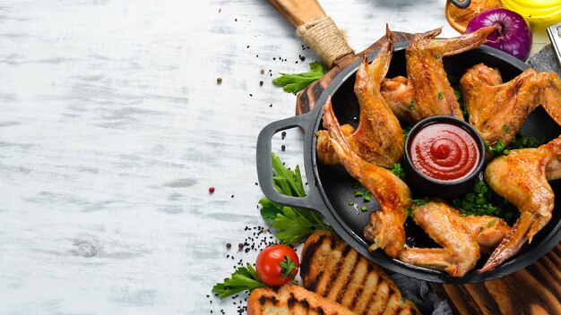 Alitas de pollo al horno en una sartén con ketchup y cebolla Barbacoa Vista superior Espacio libre para el texto