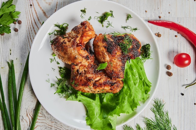 Alitas de pollo al horno con semillas de sésamo y salsa de chile dulce en una tabla de madera blanca