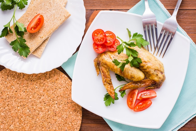 Alitas de pollo al horno con tomates cherry y perejil en un plato