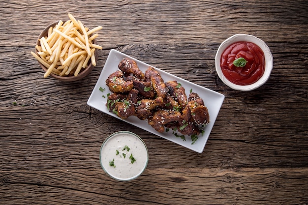 Alitas de pollo. Alas de pollo frito en tazón de fuente blanco aderezo de ajo salsa de tomate y papas fritas.