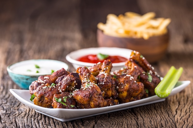 Alitas de pollo. Alas de pollo frito en tazón de fuente blanco aderezo de ajo salsa de tomate y papas fritas.