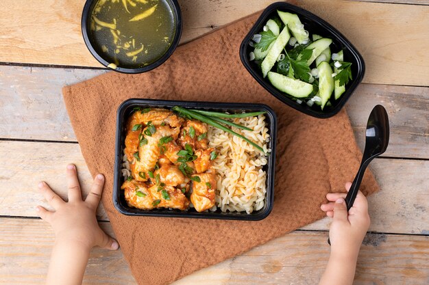 Alitas de pollo y arroz con cebolla, manos de niños con cuchara.