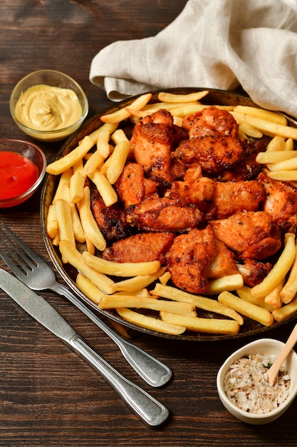 Alitas de pollo calientes y papas fritas con salsa de tomate y mostaza.