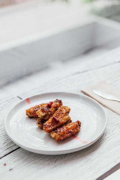 Las alitas de pollo coreanas se mezclan con una salsa estilo coreana servida en un plato blanco.