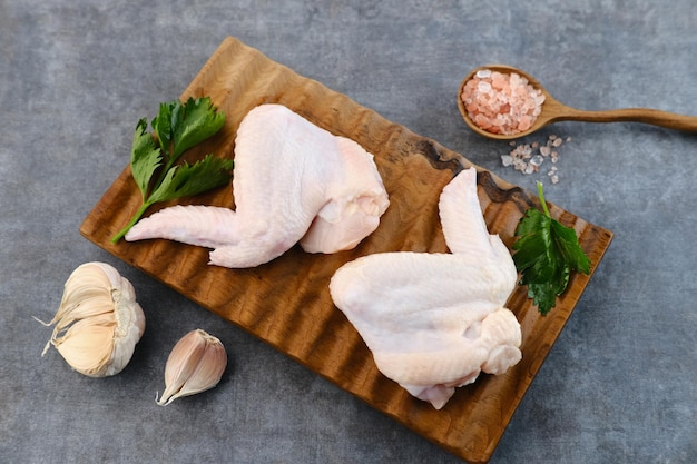 Alitas de pollo crudas frescas en tablero de madera con ingredientes preparación de alimentos