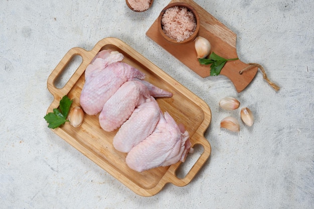 Alitas de pollo crudas sobre fondo blanco.