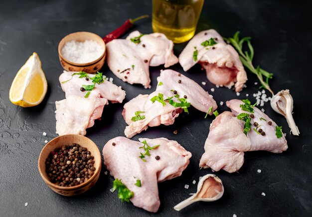 alitas de pollo crudas en una tabla de cortar con especias sobre un fondo de piedra