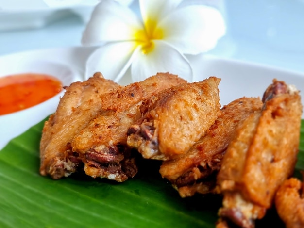 Alitas de pollo fritas en un plato con descanso y tazas de salsa para mojar en el concepto de comida y bebida