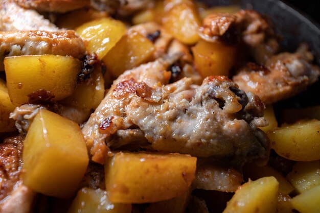 Las alitas de pollo frito con patatas se cocinan en una sartén, de cerca con poca profundidad de campo.