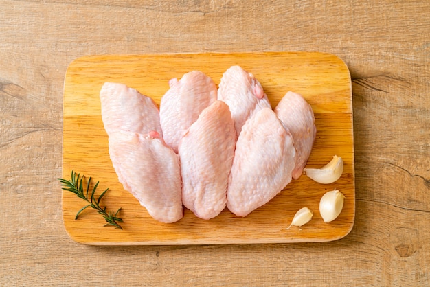 Alitas de pollo medio crudas frescas sobre tabla de madera