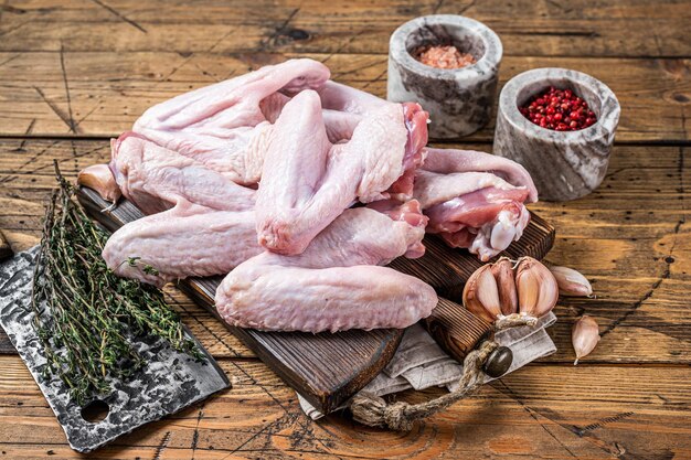 Alitas de pollo o pato crudo en una tabla de carnicero. Fondo de madera oscura. Vista superior.