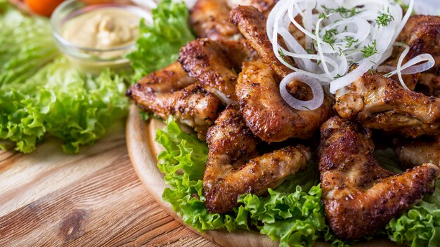 Alitas de pollo a la parrilla en bandeja de madera. Alitas de pollo a la barbacoa. .