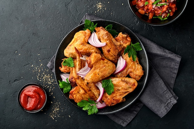 alitas de pollo a la parrilla o barbacoa asada con especias y salsa de tomate en un plato negro.