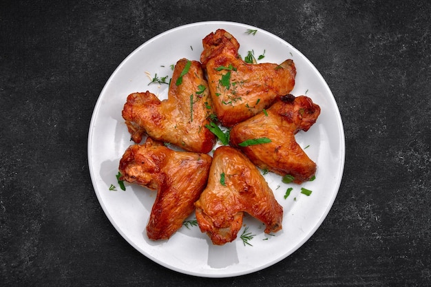 Alitas de pollo a la parrilla en un plato sobre un fondo oscuro