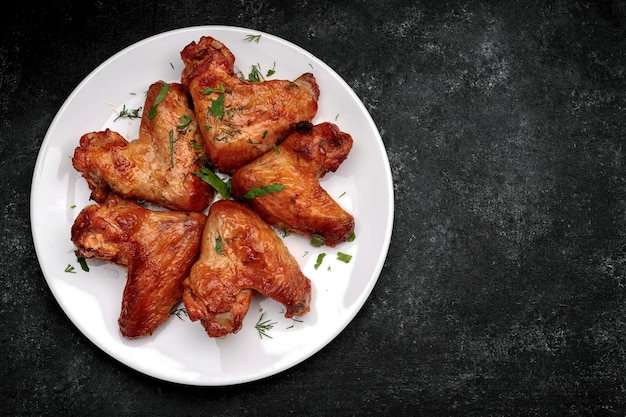 Alitas de pollo a la parrilla en un plato sobre un fondo oscuro