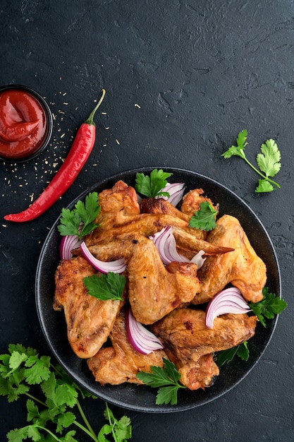 Alitas de pollo a la plancha o barbacoa asada con especias y salsa de tomate en un plato negro. vista superior