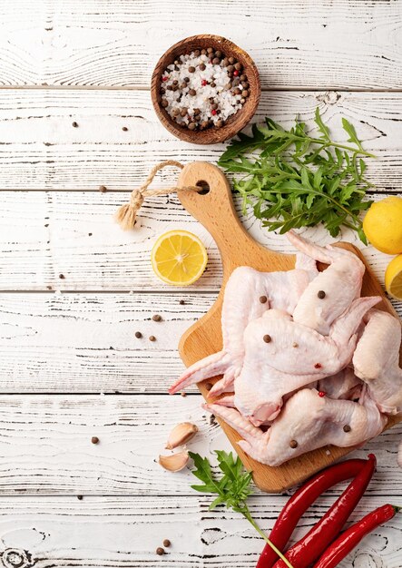 Alitas de pollo en rodajas con piel sobre una tabla para cortar Fondo de madera blanca