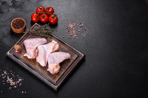 Las alitas de pollo yacen sobre una tabla de madera sobre un fondo negro