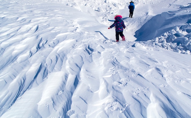 Alivio en la capa de nieve después de una tormenta de nieve, los niños bajan de la montaña