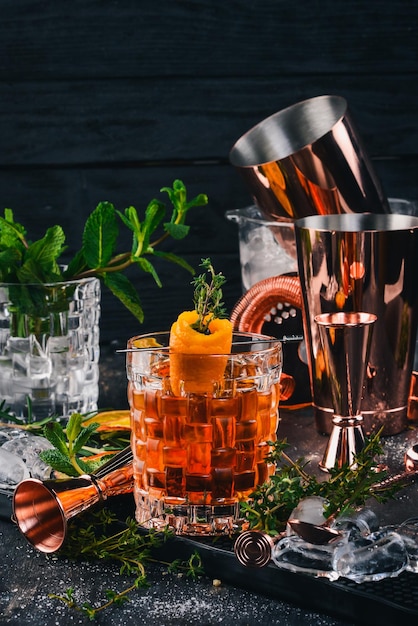 Alkohol-Cocktail Negroni Orangenliköreis auf einem schwarzen hölzernen Hintergrund