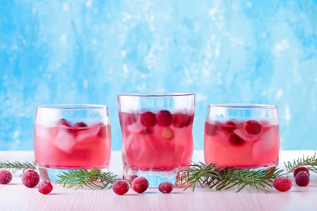 Alkoholfreier Wintercocktail mit Cranberry und Eis auf hellblauem Hintergrund, Nahaufnahme