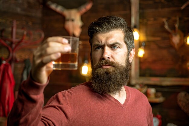 Alkoholiker mit Flasche und Glas, die nachts Whisky trinken, trinkt einen Cocktailbarmann-Hipster
