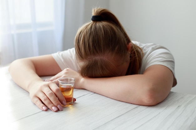 Alkoholikerin schläft auf einem Tisch mit einem Stapel starken Alkohols