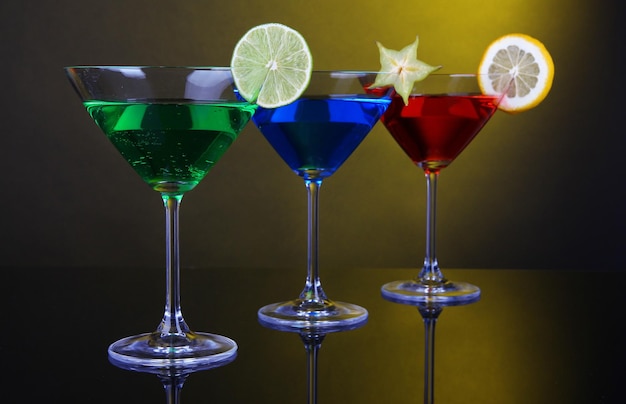 Alkoholische Cocktails in Martini-Gläsern auf dunkelgelbem Hintergrund