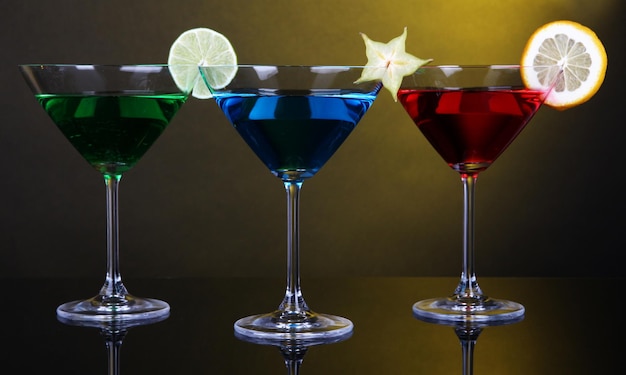 Alkoholische Cocktails in Martini-Gläsern auf dunkelgelbem Hintergrund