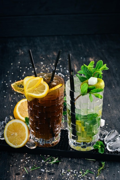 Alkoholische Cocktails Long Island und Mojito auf schwarzem Holzhintergrund