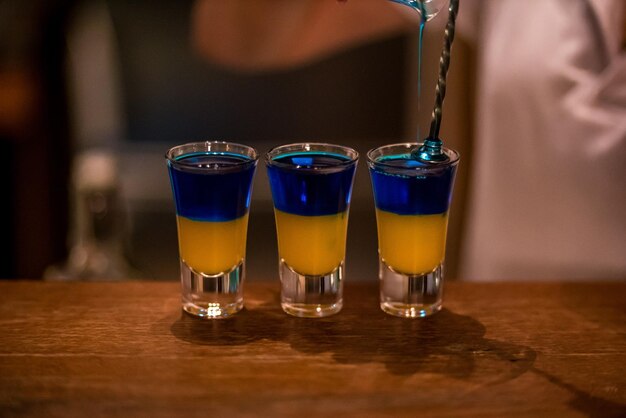 Foto alkoholische getränke in glasstapeln auf einem holztisch, blaues curaçao und zitronenlikör