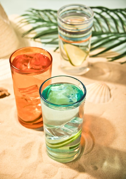 Alkoholische Sommercocktails in bunten Gläsern am Strand mit weißem Sand Sommerurlaub am Meer und Reisekonzept