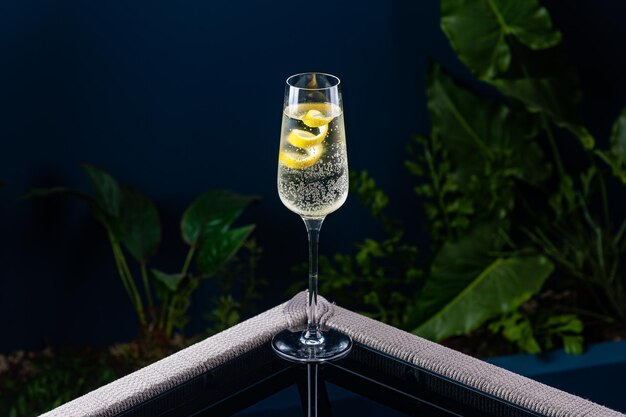 Alkoholischer Cocktail auf einem transparenten Tisch vor blauem Hintergrund und Pflanzen
