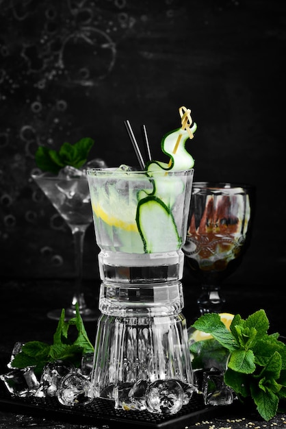 Alkoholischer Cocktail: Gin Tonic mit Gurke auf schwarzem Steinhintergrund. Menüleiste. Alkohol.