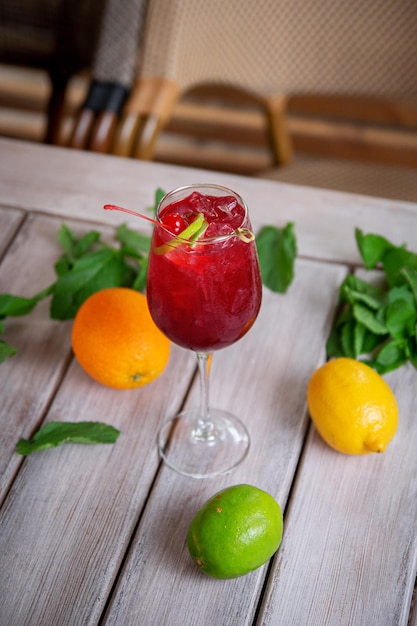 Alkoholischer Cocktail Kir Royale in einen Flötenglascocktail mit Likörwein, Limettenschale, Kirschen und Eiswürfeln gegossen