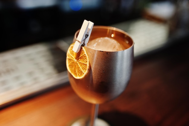 Alkoholischer Cocktail mit Eis im silbernen Glas auf Stehtisch