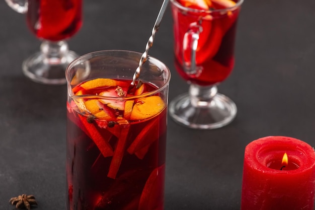 Alkoholischer Glühwein mit Früchten und Gewürzen auf dunklem Hintergrund, traditionelles alkoholisches Getränk, Weihnachten