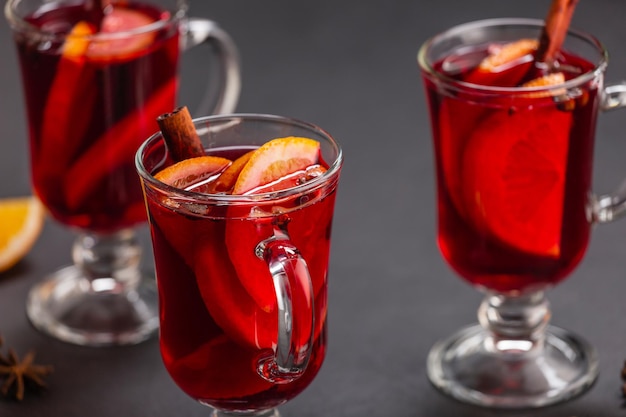 Alkoholischer Glühwein mit Früchten und Gewürzen auf dunklem Hintergrund, traditionelles alkoholisches Getränk, Weihnachten