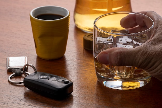 Foto alkoholmissbrauch mit einem glas whiskey mit eis und autoschlüssel auf dem tisch