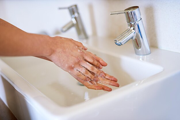 Alle Keime wegwaschen Ein Schnappschuss einer jungen Frau, die sich in ihrem Badezimmer die Hände wäscht