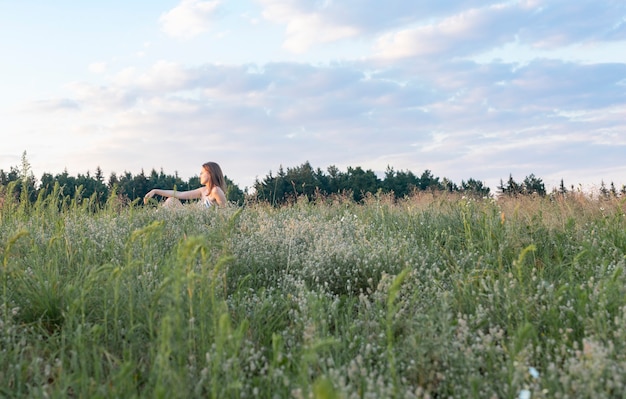 Alleine Frau sitzt auf einer Sommerwiese mit oder grüner Wiese und genießt die Natur weiblich im Freien...