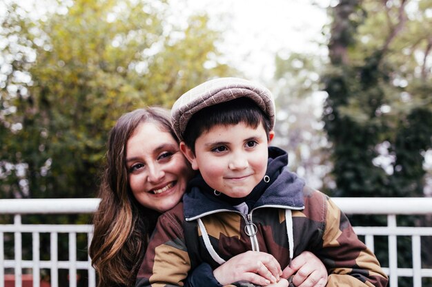 Alleinerziehende Mutter umarmt ihren kleinen Sohn im Park Alleinerziehende Familie