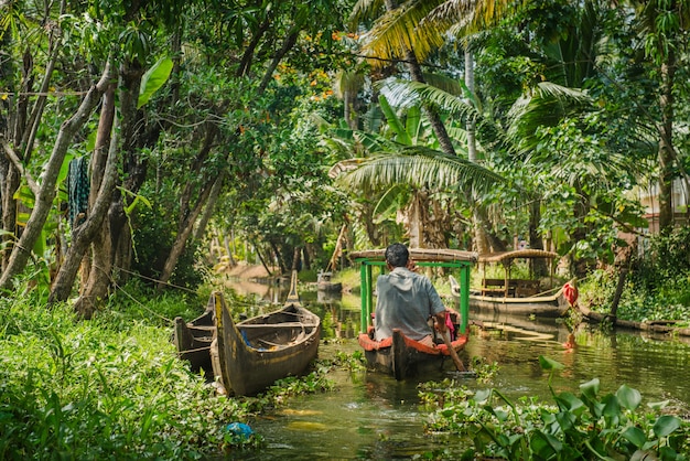 Alleppey, India - 29 de enero de 2016: Pequeño barco turístico en el hermoso paisaje de remansos con palmeras en el fondo, Kerala, India