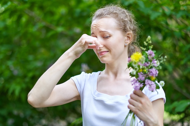 Allergie. Frau drückte ihre Nase mit der Hand, um nicht vom Blütenpollen zu niesen