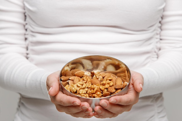 Allergie gesundes Essen Snack Frau Hände mit Mandeln und Schüssel gemischter Nüsse selektiver Fokus