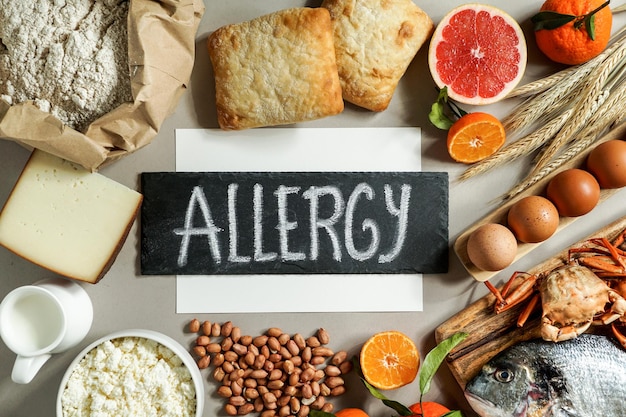 Foto allergie-lebensmittelkonzept, allergen, milch, fisch, erdbeere, brot, eier, erdnüsse, zitrusfrüchte, weizenblume und andere auf grauem hintergrund