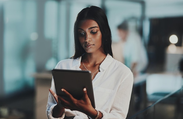 Alles auf einmal mit moderner Technologie Aufnahme einer jungen Geschäftsfrau, die nachts in einem Büro ein digitales Tablet verwendet