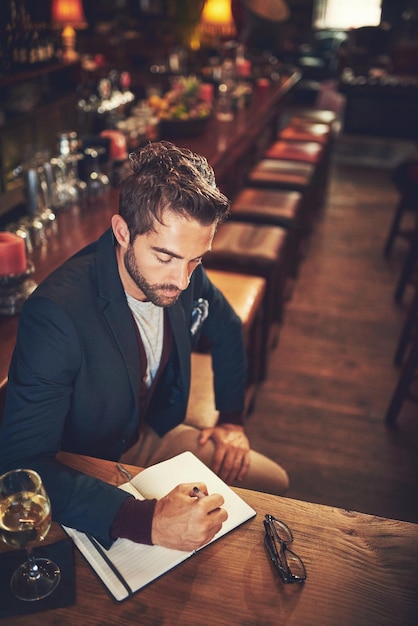 Alles beginnt mit einer Handlung Hochwinkelaufnahme eines jungen Mannes, der mit seinem Tagebuch in einer Bar sitzt