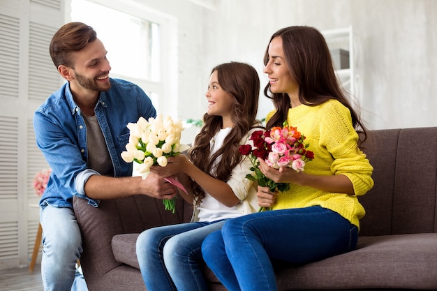 Alles Gute zum Mutter- oder Frauentag. Aufgeregte und schöne Familie, die den Tag der Frauen feiert. Der Ehemann hat für seine Frau und seine kleine süße Tochter eine Überraschung vorbereitet