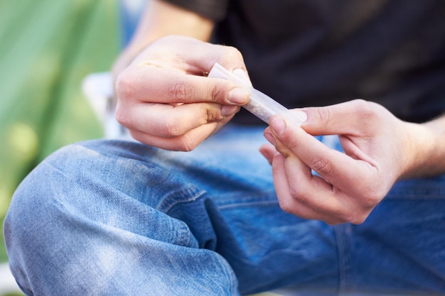 Alles hat ein Tor Aufnahme einer nicht erkennbaren Person, die einen großen Marihuana-Joint dreht